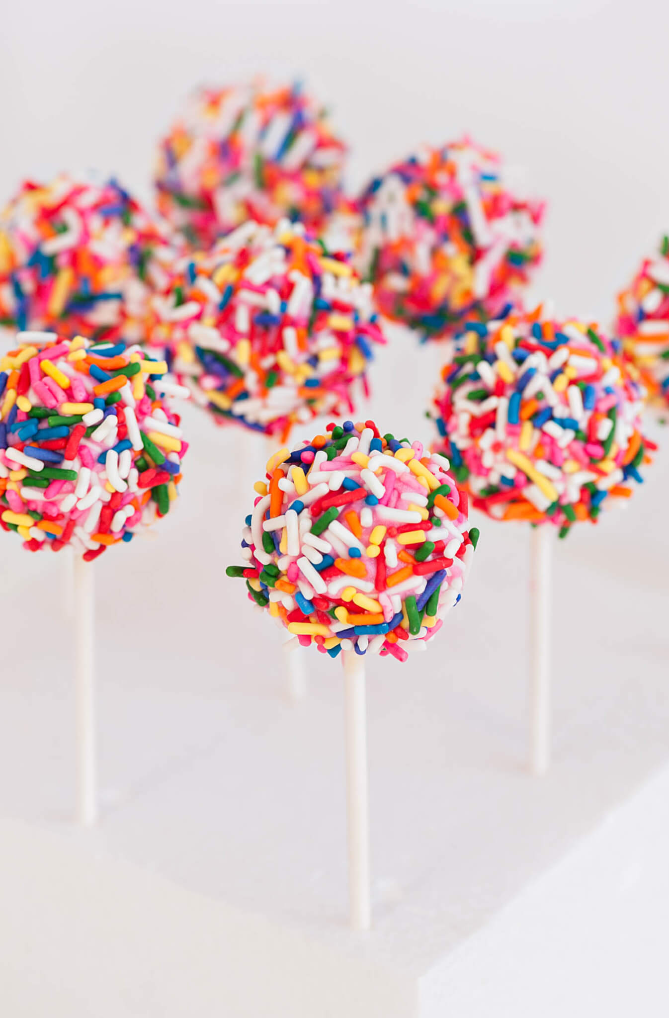 Cluster of Confetti Cake Pops displayed on a white cake pop stand 