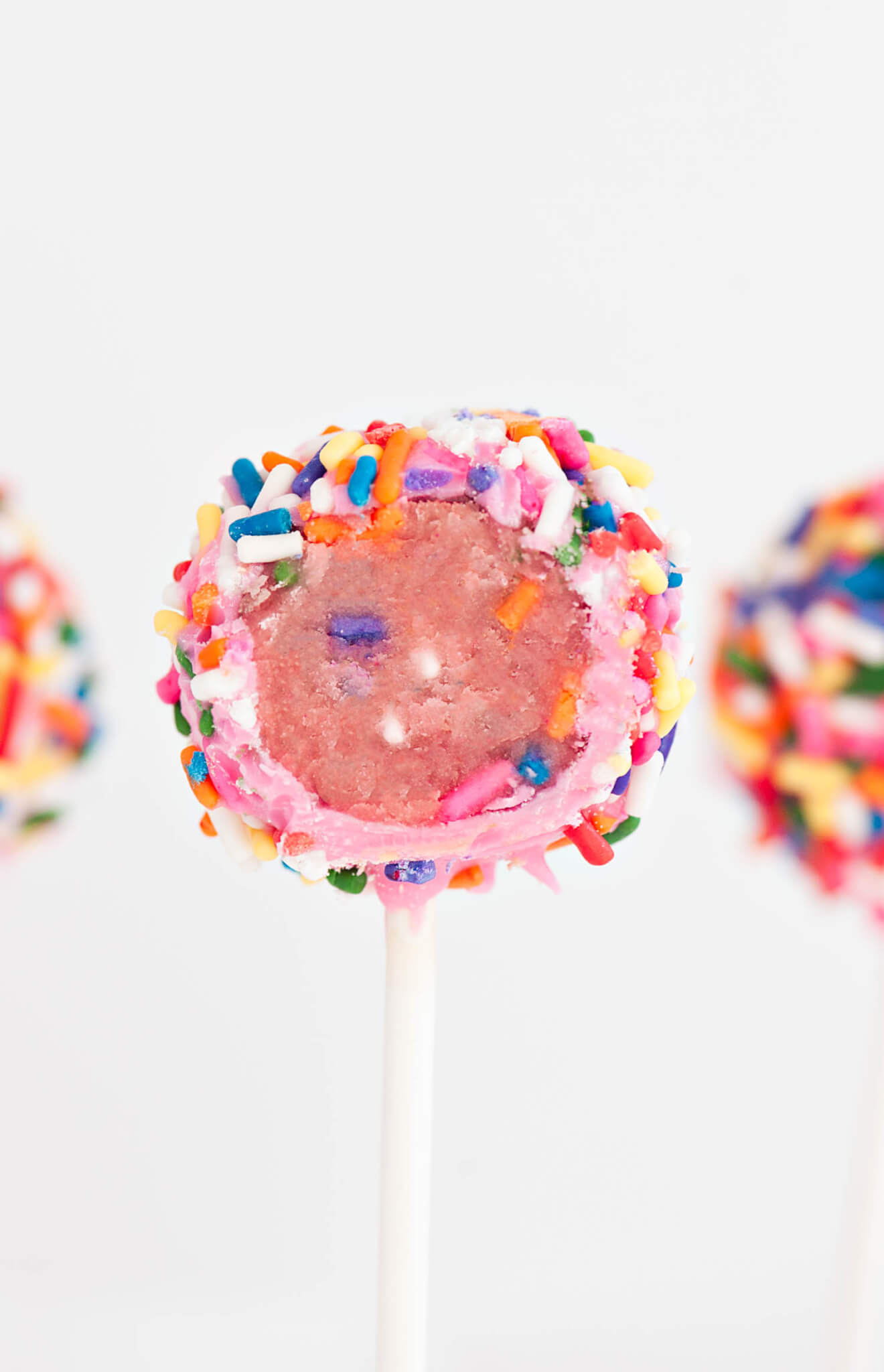 Close up of a Strawberry Confetti Cake Pop with a bite taken out of it. 